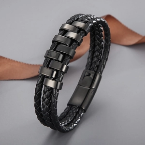 Detail of multi-layer braided leather bracelet with gunmetal magnetic clasp on grey background