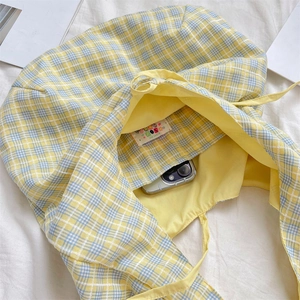 Detail of yellow and blue plaid tote bag showing inner lining and colorful woven label
