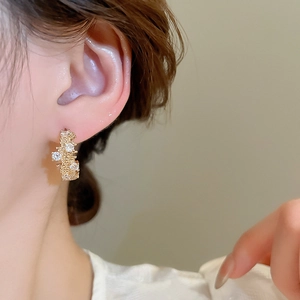 Close-up of vintage gold geometric earrings with sparkling zircon crystals on model