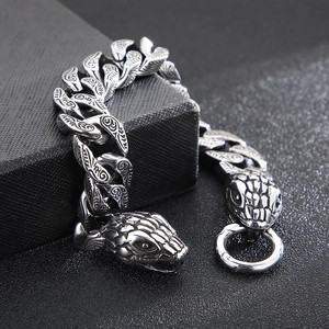 Macro detail of antique silver double snake head clasps on a punk steel Cuban chain bracelet