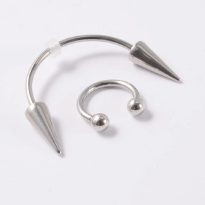 Detail of silver stainless steel horseshoe lip rings with spike and ball ends on white background