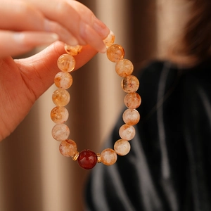 Vue macro d'un bracelet de perles de cristal orange translucide avec pierre centrale rouge