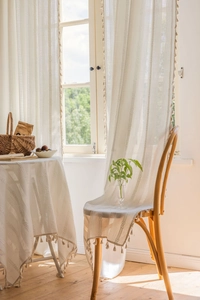 Close-up of cream white vertical jacquard curtain with elegant tassel trim decoration
