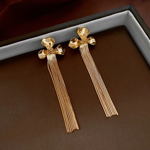 Detail view of gold-plated flower stud earrings with long sleek snake chain tassels