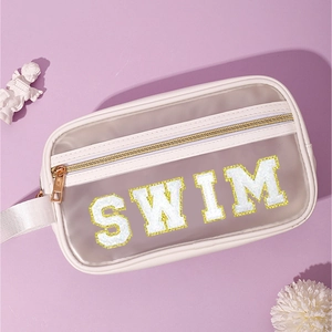 Dettaglio delle lettere SWIM in ciniglia bianca sulla borsa cosmetica in PVC trasparente