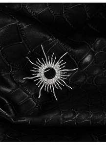 Macro shot of silver sunburst brooch with clear cubic zirconia on black leather