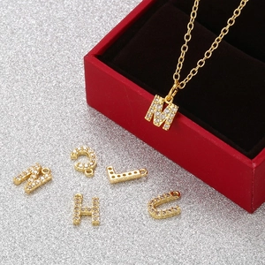 Detailed macro view of S925 sterling silver gold alphabet charms with shiny zirconia inlays