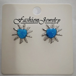 Detailed macro view of heart-shaped silver earrings with blue faux opal inlay on white card