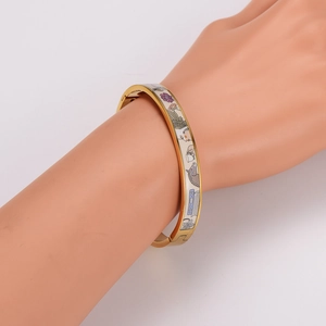 Golden enamel bangle featuring intricate horse and floral patterns on a white base