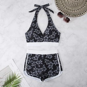 Flat lay of floral halter bikini with high-waisted bottoms on white marble surface