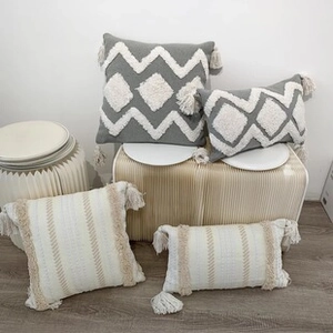 Detailed view of tufted geometric patterns and boho tassels on woven cushion covers