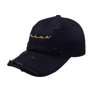 Close-up of golden mama embroidery on distressed black cotton twill baseball cap