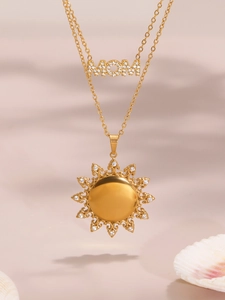 Macro detail van gouden gelaagde ketting met MOM-hanger en kristallen zon hanger