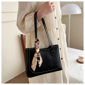Détail d'un sac cabas en cuir noir avec surpiqûres blanches et accessoire foulard en soie