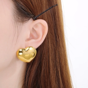 Gros plan de boucles d'oreilles cœur dorées élégantes portées par un mannequin chic