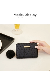 Detail of black quilted leather coin purse with golden metal bar and plush pompom charm
