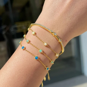 Detail of layered gold S925 silver bracelet with sparkling opal and zircon stones