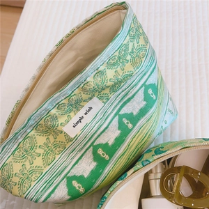 Detail of floral jacquard makeup bag showing green woven fabric and zipper closure