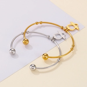 Detail of owl charms and beads on gold and silver open bangles over split background