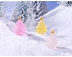 Miniature glowing Christmas trees in pink, yellow and white on a snowy base decoration