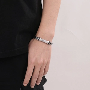 Detail of men's steel bracelet featuring silver metal plate and black woven wire cable
