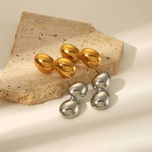 Boucles d'oreilles polies en forme de haricot dorées et argentées sur présentoir pierre