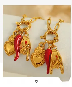 Detailed shot of golden chain with heart, red chili, and hand gesture charms