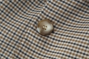 Macro shot of houndstooth woven fabric and high-quality brown resin button detail