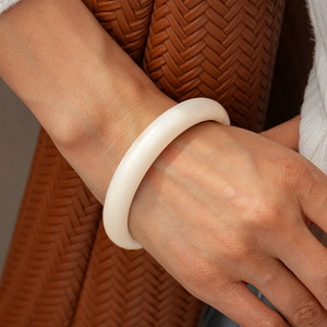 Close-up of minimalist cream white acrylic bangle with smooth glossy finish on wrist