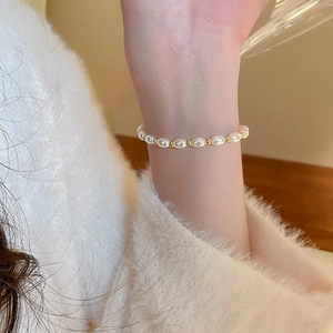 Elegant pearl bracelet with white oval pearls and gold beads on a model wrist