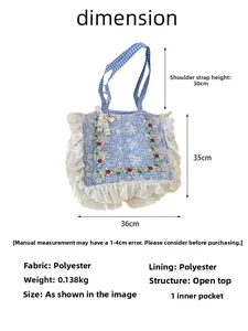 Detail view of floral embroidery and white lace trim on blue plaid canvas tote bag