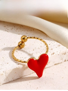 Macro detail of gold-plated ring featuring red enamel heart and diamond-cut texture