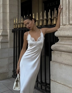 Detalle del vestido de satén blanco con encaje delicado en el escote en V y tirantes