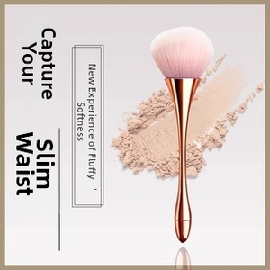 Detail of powder brush with pink bristles and rose gold waisted handle on powder background