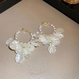 Elegant gold hoop earrings with white pearls and hanging translucent flower petals