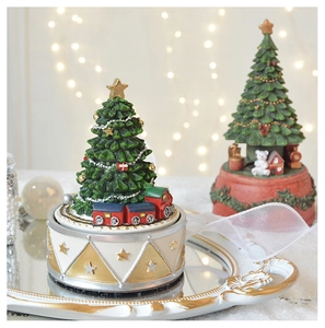 Detailed close-up of a rotating Christmas tree music box with miniature trains on a gold tray