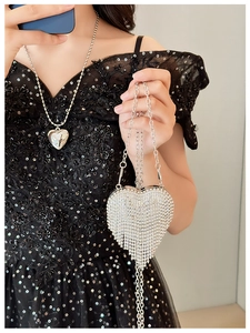 Close-up of heart-shaped silver evening bag with rhinestones and elegant long tassels
