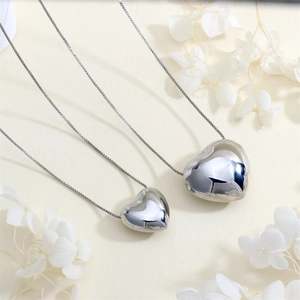 Macro shot of polished silver heart necklaces on white floral background with chain details