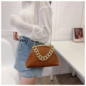 Detail of a brown quilted trapezoid bag with elegant gold chain strap and vintage clasp