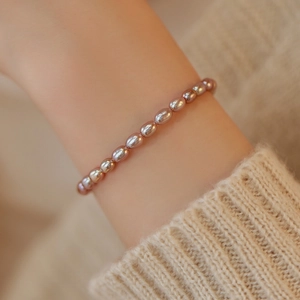 Detail of light purple freshwater pearl bracelet on wrist with beige knit sweater