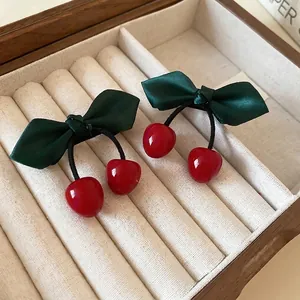 Fresh cherry hair clips with red berries and green satin leaf bows in a beige jewelry box
