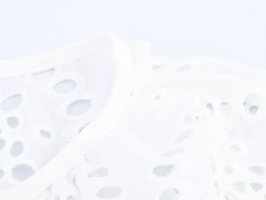 Close-up detail of white hollow embroidery lace fabric with circular floral patterns