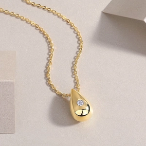 Macro shot of gold teardrop pendant necklace with a round sparkling moissanite stone