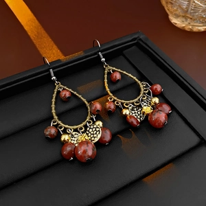 Detail of bohemian drop earrings with bronze metal and red-brown beads on black leather