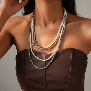 Close-up of layered faux pearl necklace with floral OT clasp on elegant model