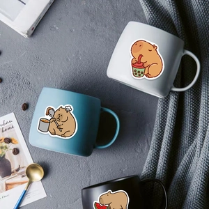 Ceramic capybara mugs in white, blue and black arranged on a cozy grey textured blanket
