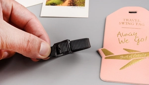 Detail of pink faux leather luggage tag with gold foil plane and travel text motifs