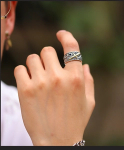 Detail of vintage wide silver ring featuring golden cross and blue gemstone on finger