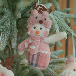 Pink and white plush snowman ornament with reindeer hat and checkered scarf on tree