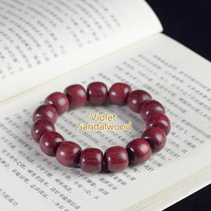 Macro shot of polished purpleheart wood barrel beads bracelet on a classic book page